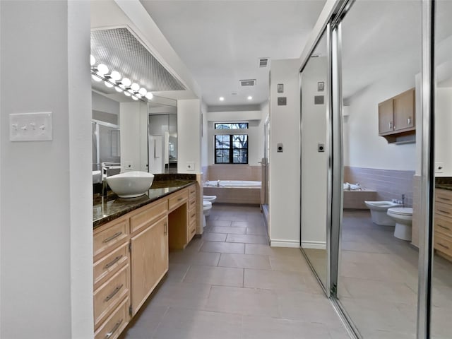 bathroom featuring a bidet, vanity, toilet, and a bath