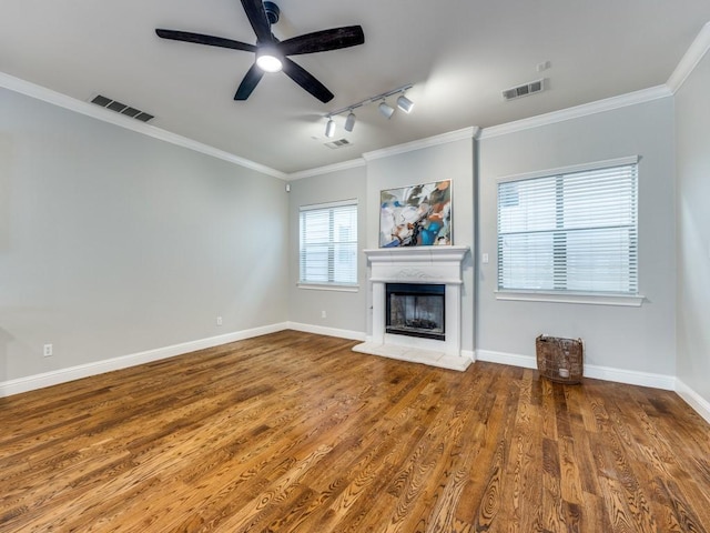 unfurnished living room with crown molding, wood finished floors, a fireplace with raised hearth, and visible vents