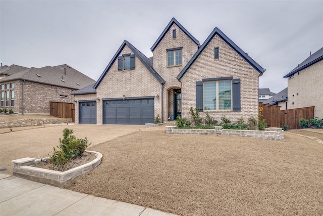 view of front of house with a garage, concrete driveway, brick siding, and fence