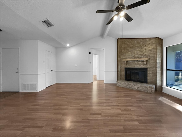 unfurnished living room featuring dark wood-style flooring, visible vents, a fireplace, and a textured ceiling