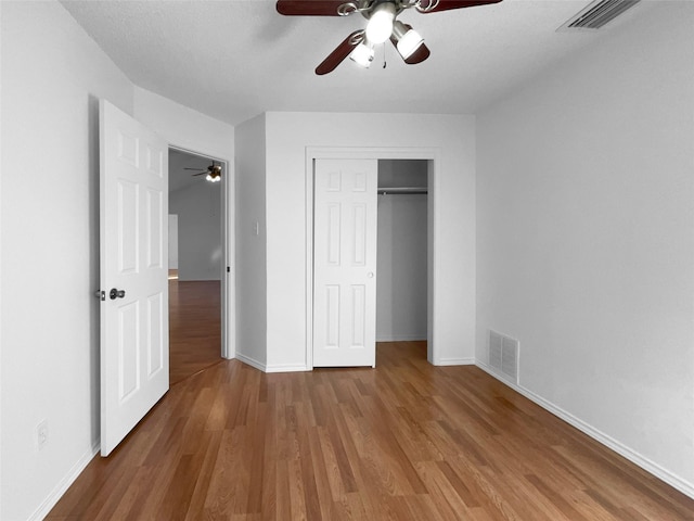 unfurnished bedroom featuring a closet, visible vents, and wood finished floors