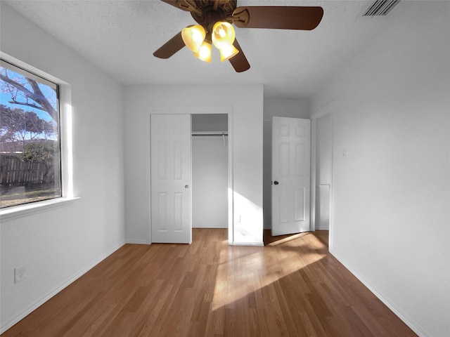 unfurnished bedroom with baseboards, visible vents, ceiling fan, light wood-style floors, and a closet