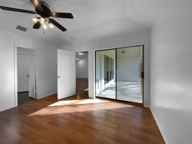 unfurnished bedroom with baseboards, visible vents, dark wood finished floors, and a textured ceiling