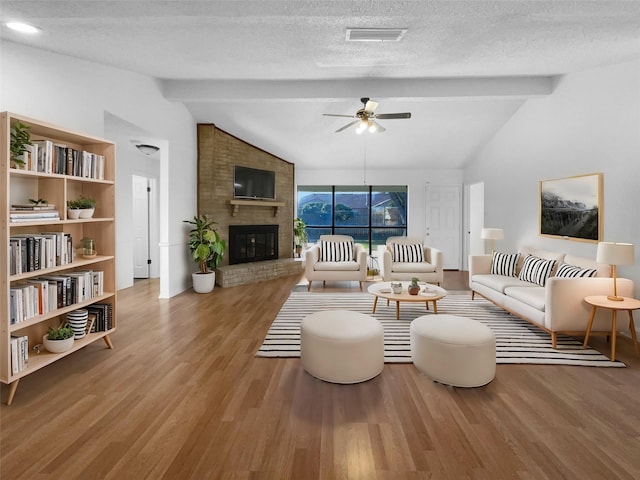 living room featuring vaulted ceiling with beams, a textured ceiling, visible vents, and wood finished floors