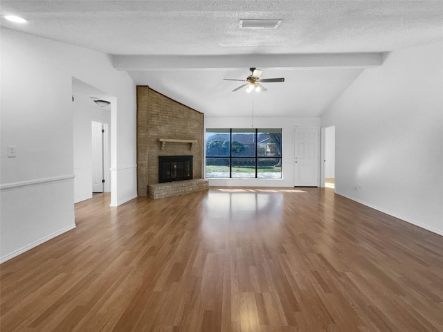 unfurnished living room with vaulted ceiling with beams, ceiling fan, a brick fireplace, and visible vents