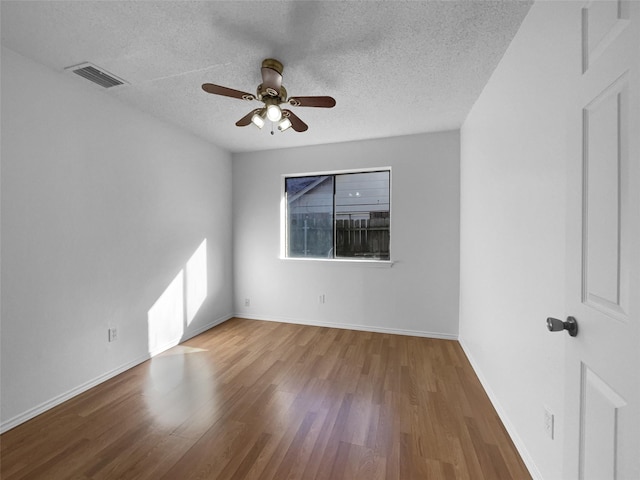 unfurnished room featuring a textured ceiling, ceiling fan, visible vents, baseboards, and light wood-type flooring