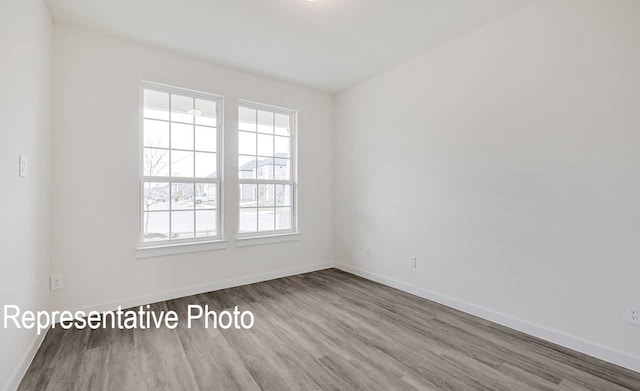 empty room with baseboards and wood finished floors