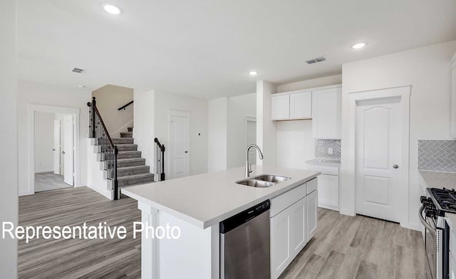 kitchen with a sink, white cabinets, light countertops, appliances with stainless steel finishes, and an island with sink