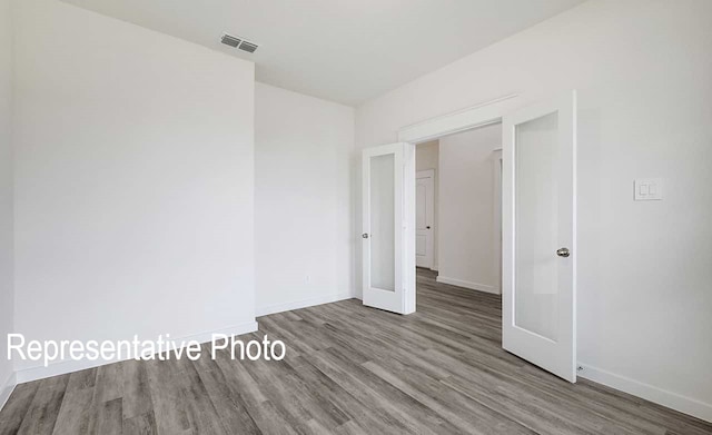 spare room featuring baseboards, visible vents, and wood finished floors