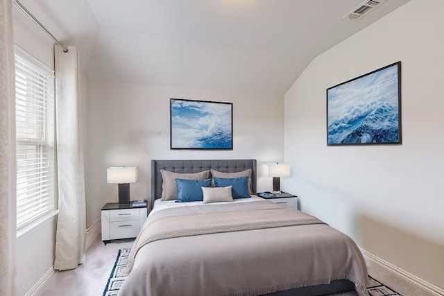 bedroom featuring lofted ceiling, visible vents, light carpet, and baseboards