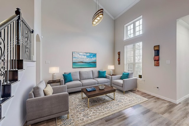 living room with baseboards, arched walkways, a towering ceiling, wood finished floors, and crown molding