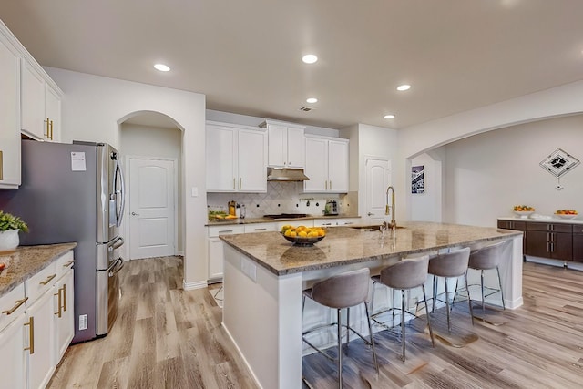 kitchen featuring arched walkways, a kitchen breakfast bar, a sink, and decorative backsplash