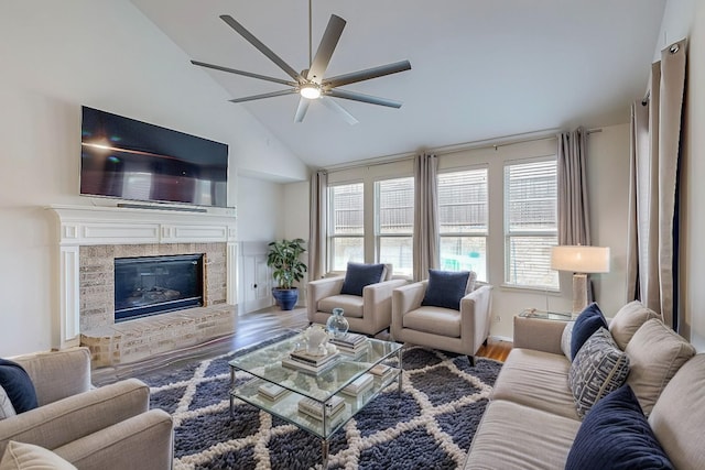 living room featuring ceiling fan, a brick fireplace, vaulted ceiling, and wood finished floors