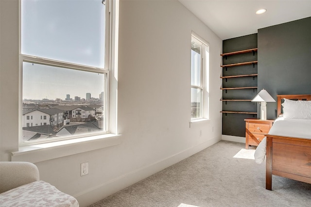 bedroom with recessed lighting, light carpet, a city view, and baseboards