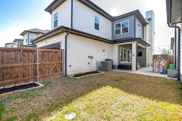 back of property with a patio, an attached garage, central air condition unit, fence, and a lawn