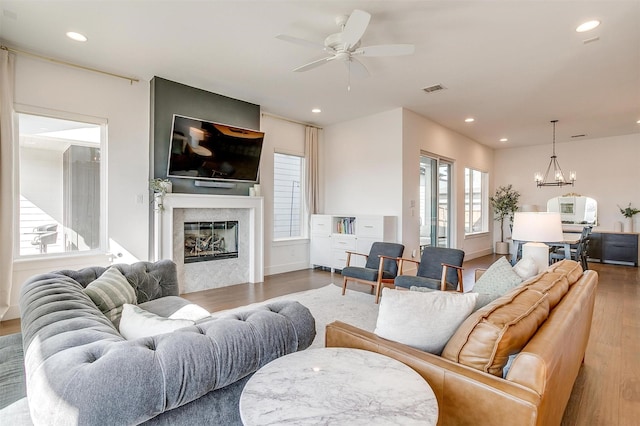 living area featuring a glass covered fireplace, a healthy amount of sunlight, visible vents, and wood finished floors