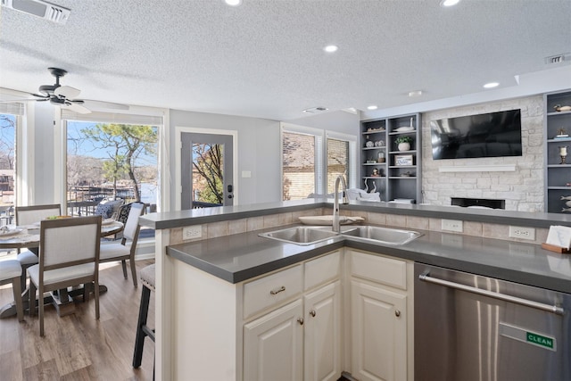 kitchen with visible vents, dishwasher, dark countertops, open floor plan, and a sink