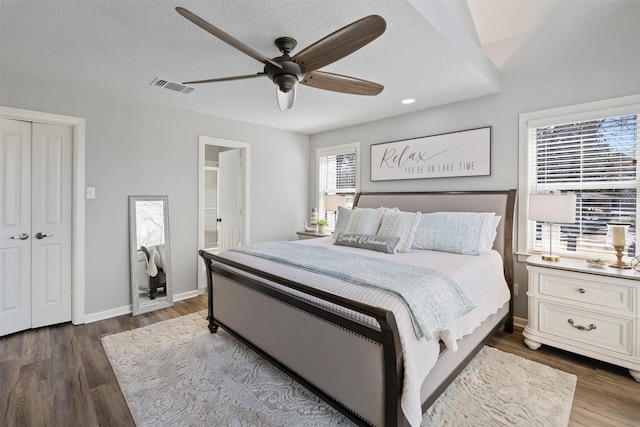 bedroom with a textured ceiling, wood finished floors, a ceiling fan, visible vents, and baseboards