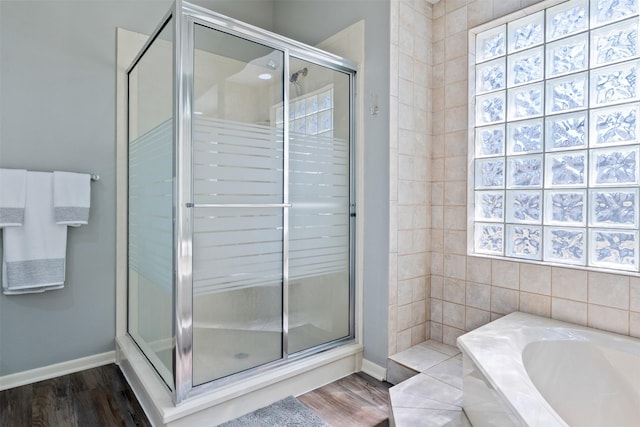 full bath with baseboards, a shower stall, a bath, and wood finished floors