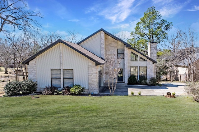 back of property with stone siding, a yard, a chimney, and fence