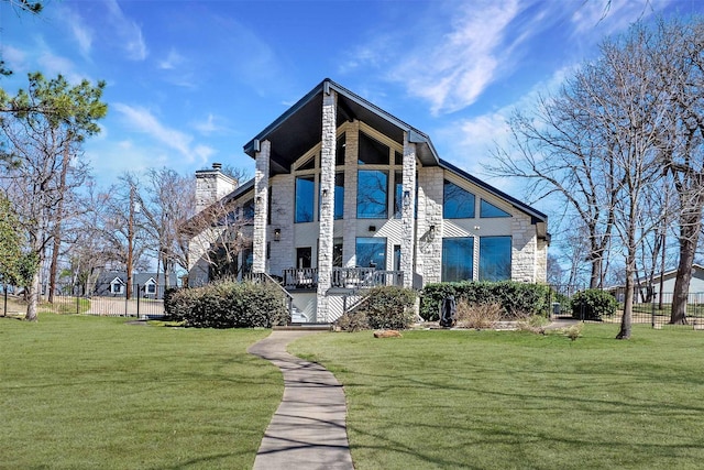 view of front of home featuring stone siding, a front lawn, a chimney, and fence