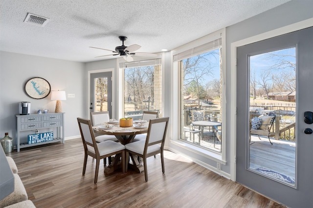 dining area with visible vents, a textured ceiling, and wood finished floors