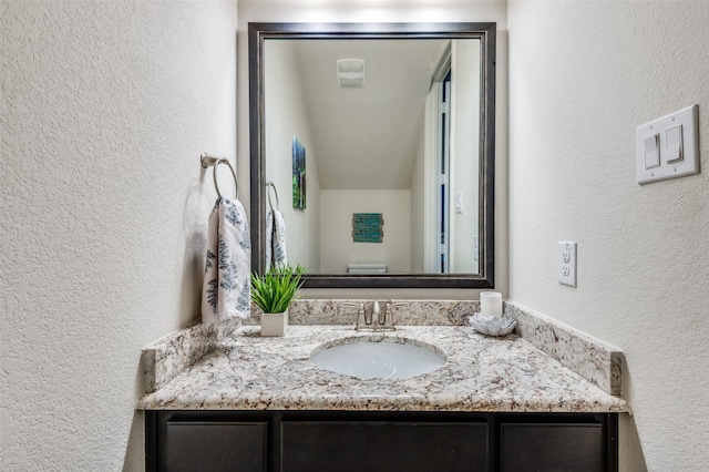 bathroom with a textured wall and vanity