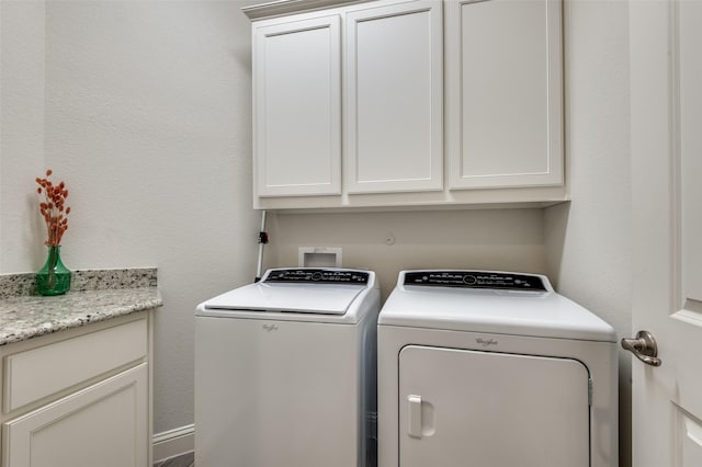 clothes washing area featuring cabinet space and separate washer and dryer