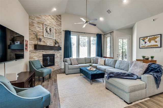 living room with a stone fireplace, light wood-type flooring, and a healthy amount of sunlight