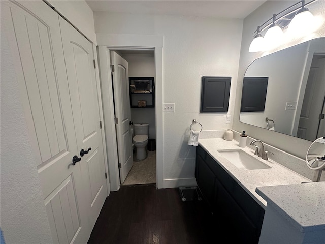 bathroom with vanity, wood finished floors, toilet, and baseboards