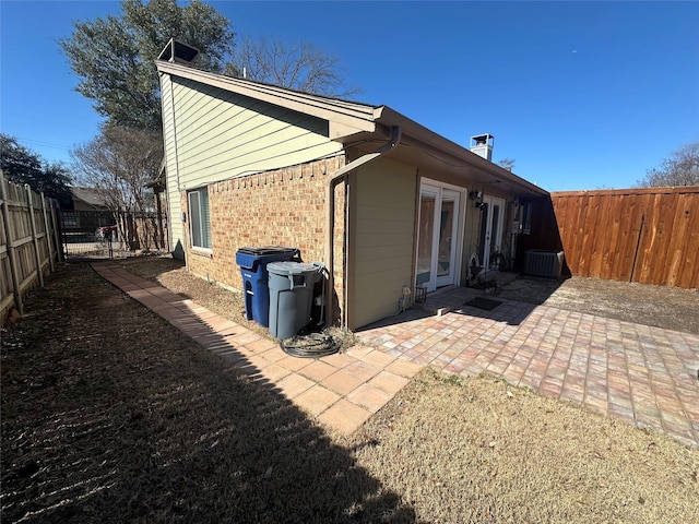 rear view of house featuring a fenced backyard, brick siding, and a patio