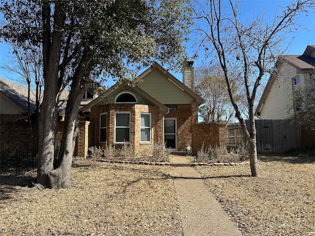 view of front of home featuring a chimney, fence, and brick siding