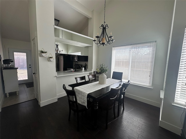 dining space featuring dark wood-style floors, baseboards, and an inviting chandelier