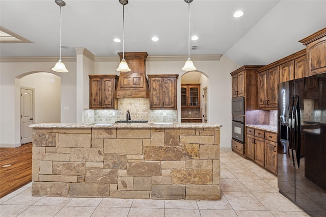 kitchen with arched walkways, pendant lighting, a large island, and black appliances