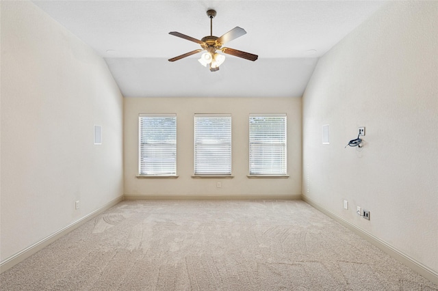 empty room featuring lofted ceiling, ceiling fan, light colored carpet, and a healthy amount of sunlight