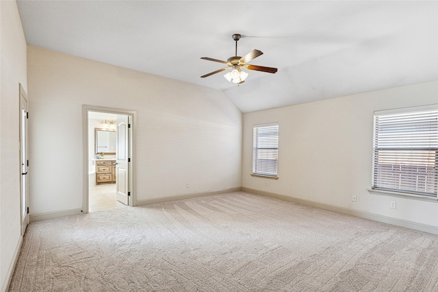 spare room featuring vaulted ceiling, light colored carpet, ceiling fan, and baseboards