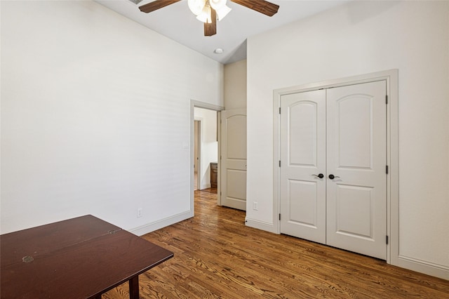 unfurnished bedroom featuring ceiling fan, a closet, wood finished floors, and baseboards