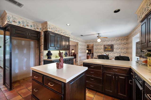 kitchen with light countertops, dark brown cabinets, a peninsula, and wallpapered walls