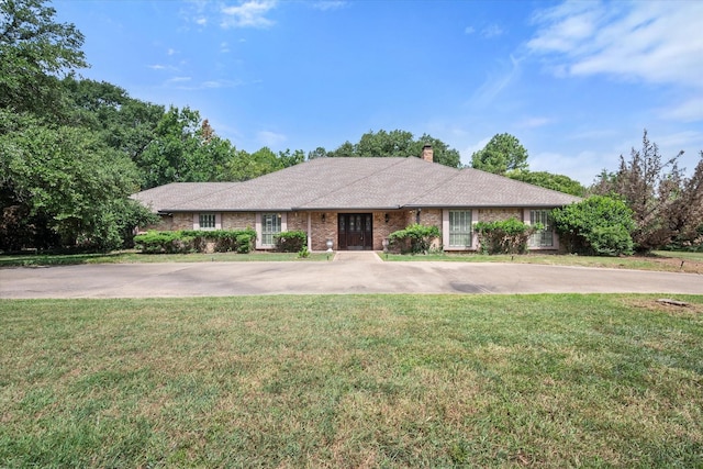 single story home featuring a front yard, brick siding, driveway, and a chimney