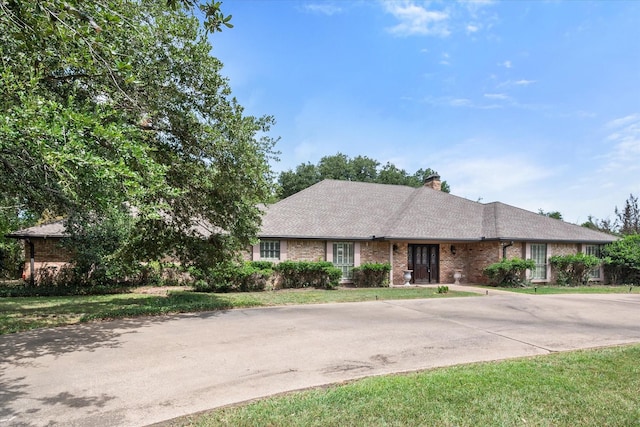 ranch-style house with driveway, a front lawn, and brick siding