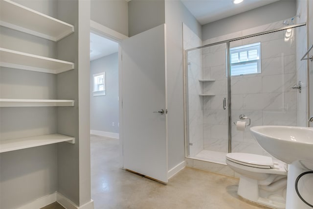 bathroom featuring concrete floors, a stall shower, plenty of natural light, and baseboards