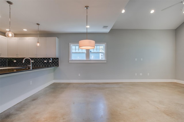 kitchen featuring decorative light fixtures, dark countertops, visible vents, backsplash, and white cabinetry