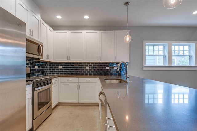 kitchen with appliances with stainless steel finishes, dark countertops, white cabinetry, and a sink