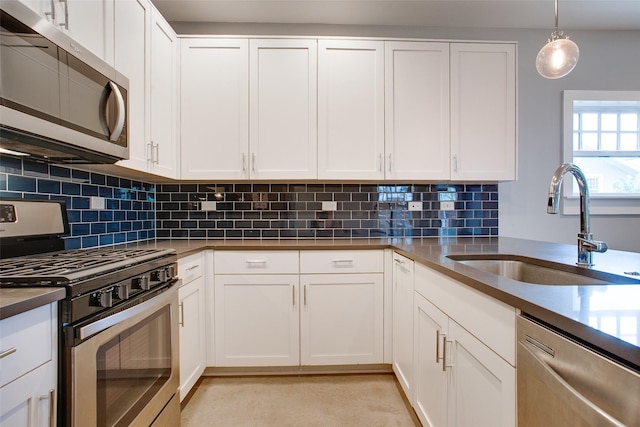 kitchen featuring decorative light fixtures, a sink, stainless steel appliances, white cabinetry, and backsplash