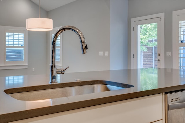 kitchen with dark countertops, pendant lighting, and a sink