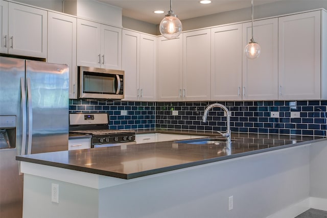 kitchen featuring stainless steel appliances, dark countertops, decorative light fixtures, and white cabinets