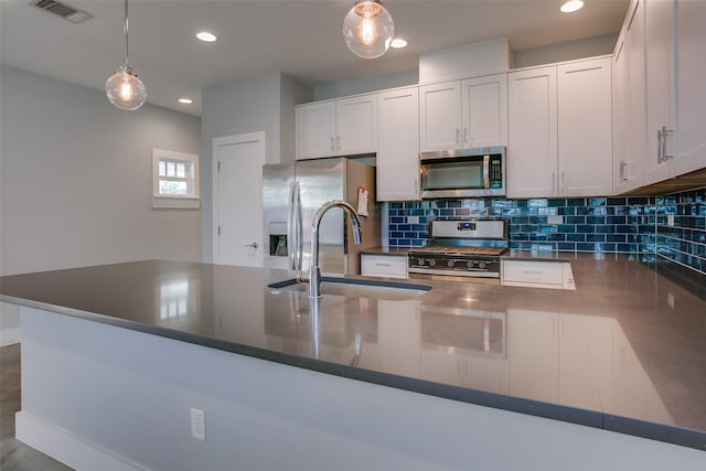 kitchen featuring visible vents, white cabinets, dark countertops, stainless steel appliances, and a sink