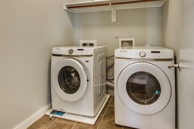 laundry room featuring washing machine and dryer, laundry area, dark tile patterned floors, and baseboards