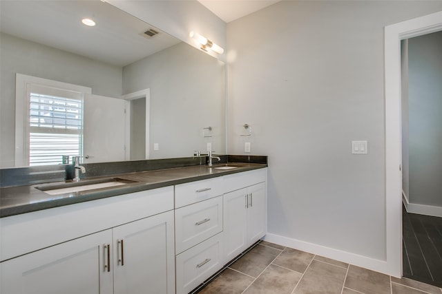 bathroom with visible vents, a sink, baseboards, and double vanity