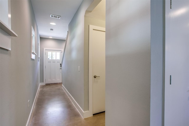 corridor with baseboards, visible vents, and finished concrete floors